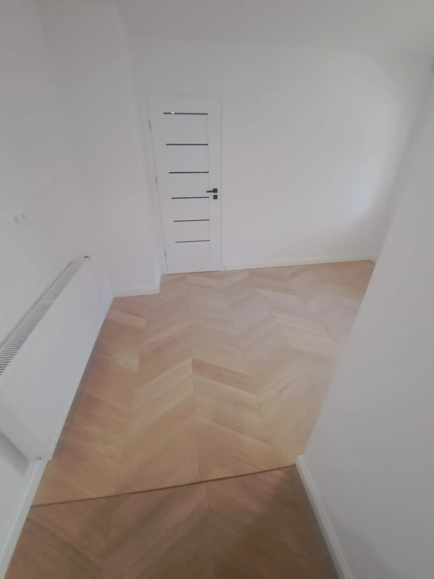 Nowoczesna podłoga z układaniem paneli w jasnym pomieszczeniu z białymi ścianami